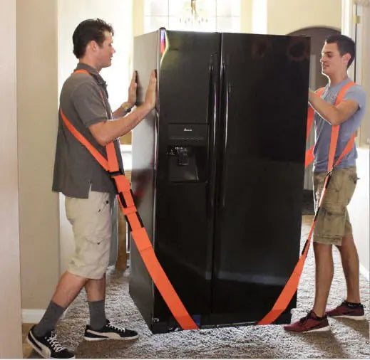 Two individuals are using orange moving straps to lift and move a heavy appliance, such as a refrigerator, across a room.