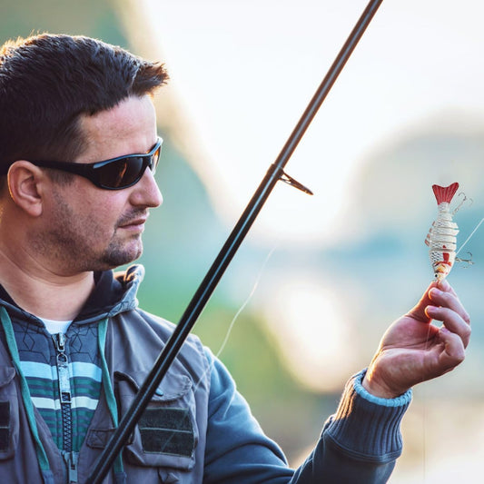 A man holding a fishing rod and lure with a blurred natural background