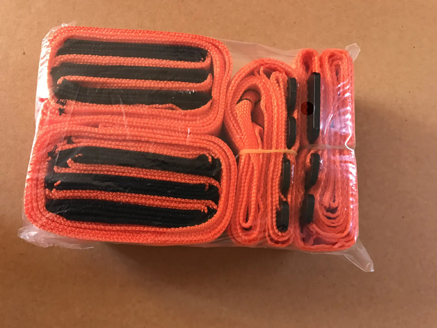 Two individuals are using orange moving straps to lift and move a heavy appliance, such as a refrigerator, across a room.